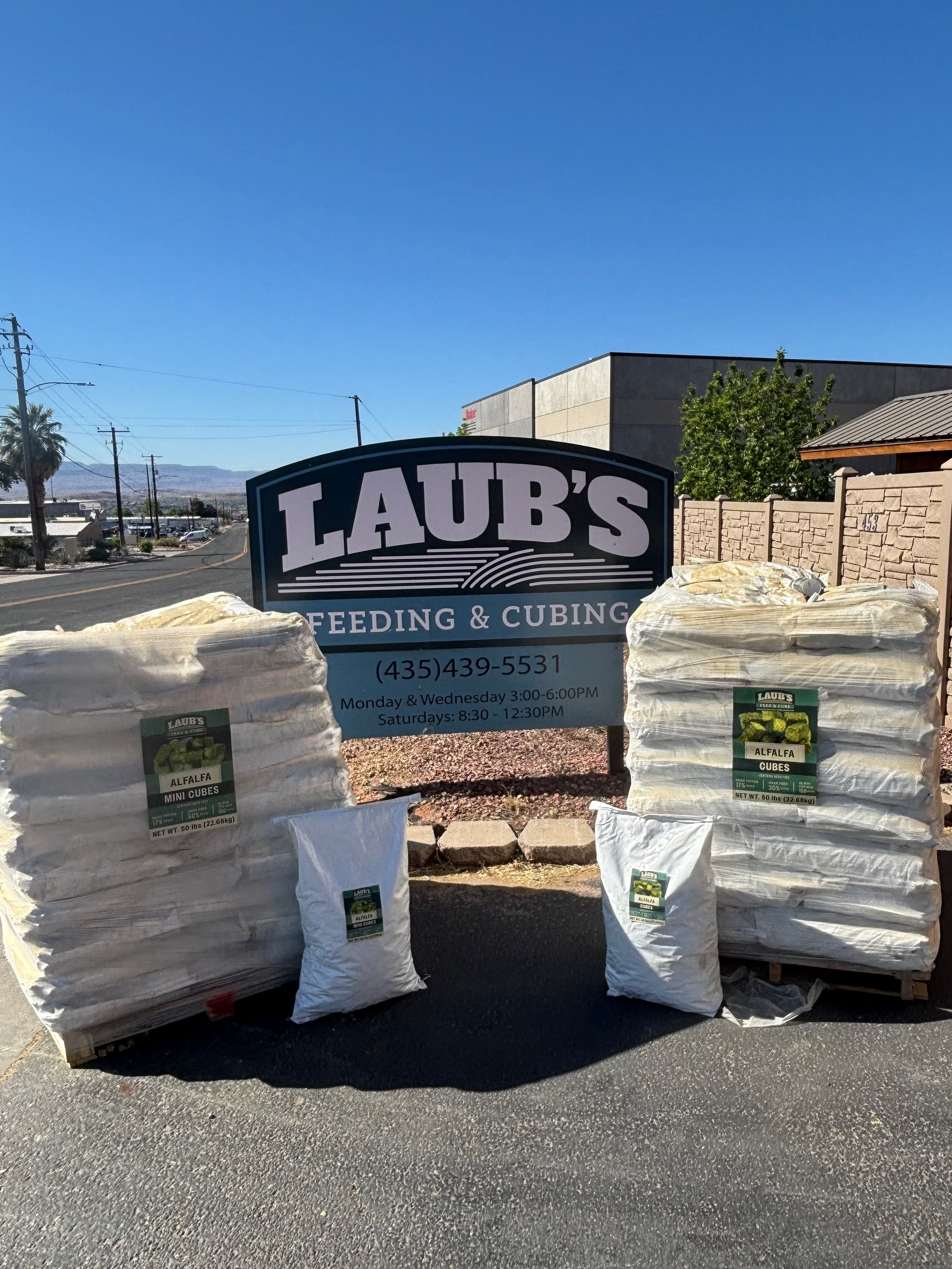 Stacks of feed bags on a road with 'Laub's Feeding & Cubing' sign 